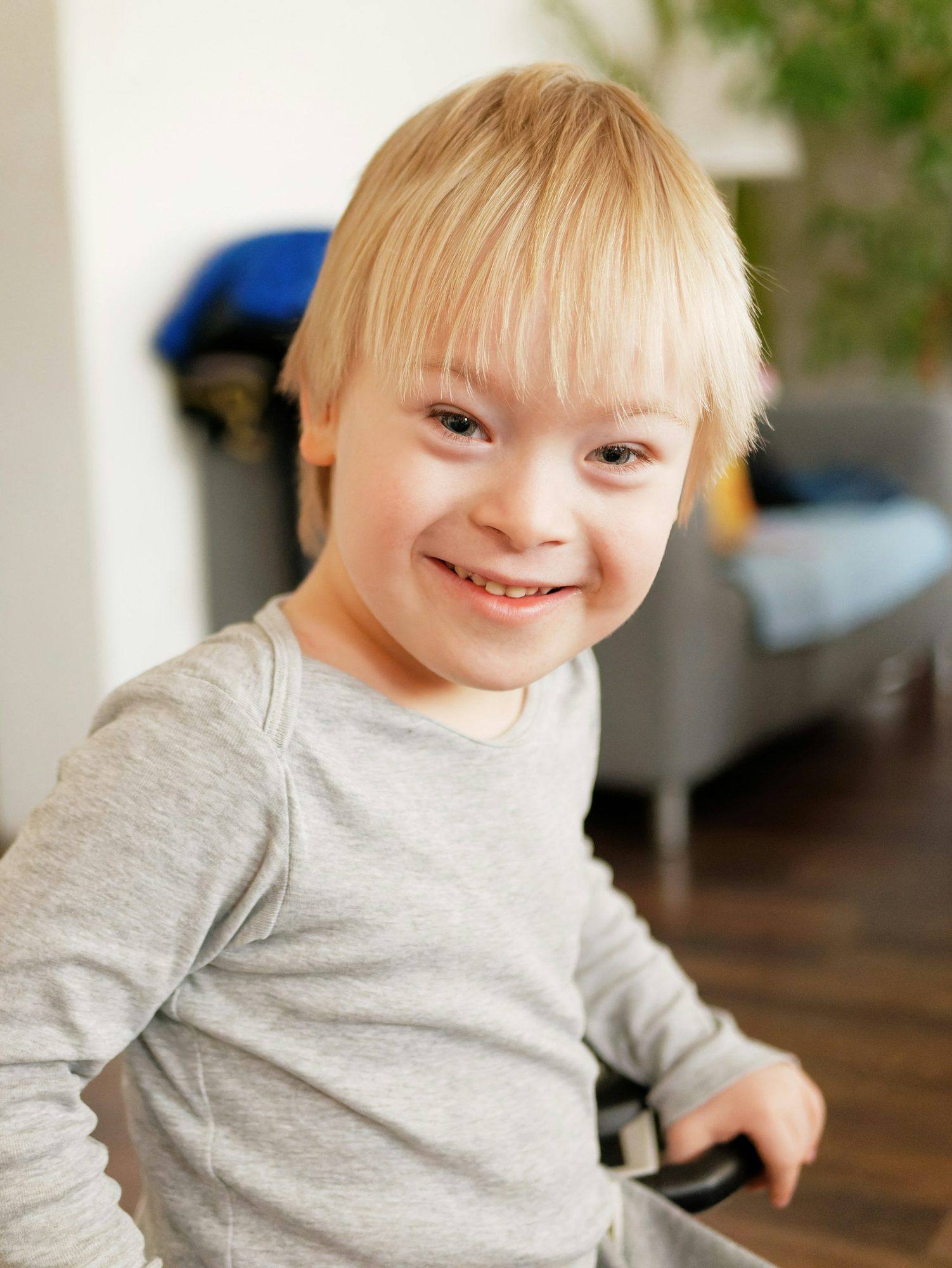 A smiling young boy sitting in a chair at home