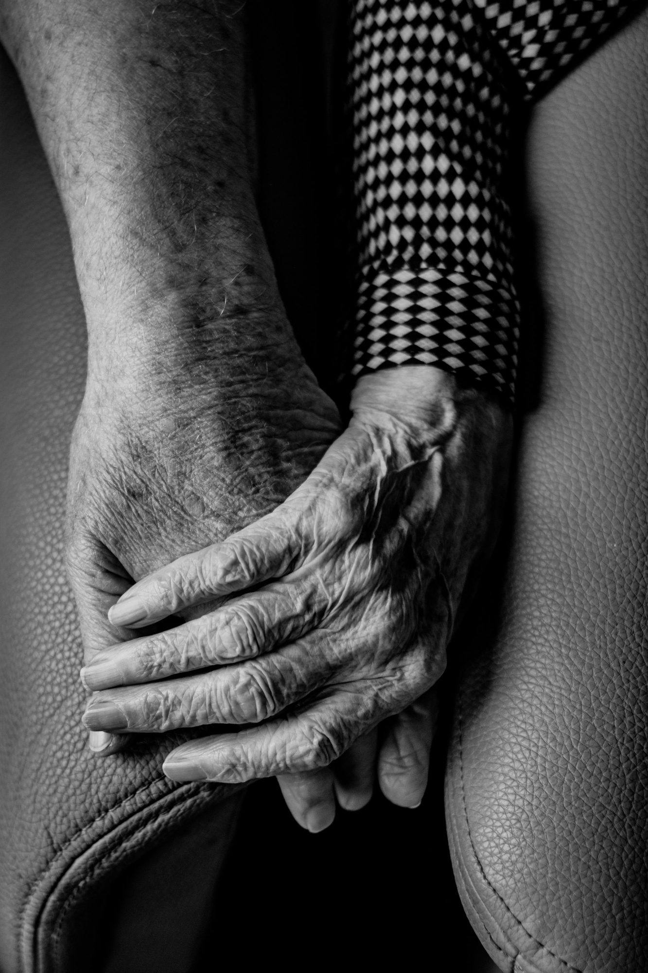 Black and white close-up of an older person's hands resting together