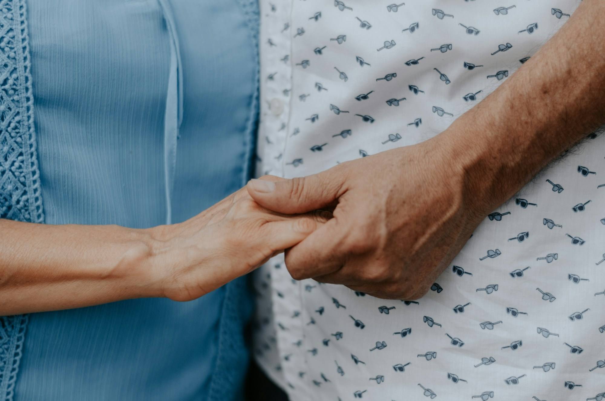 Two people holding hands, one in a patterned shirt