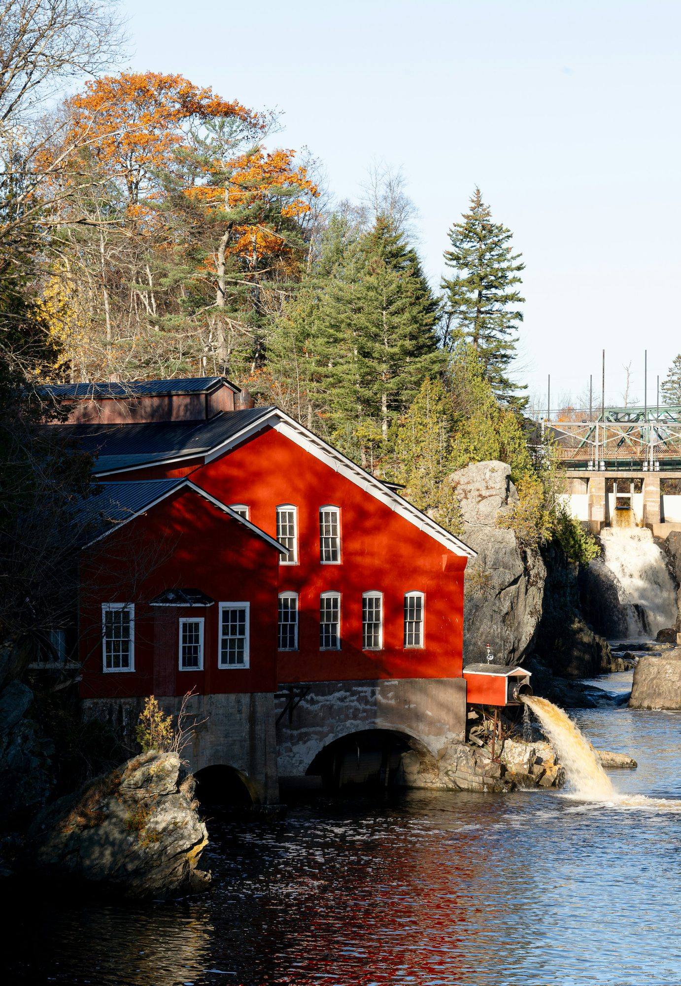 A red mill building beside a waterfall in Saint John in autumn